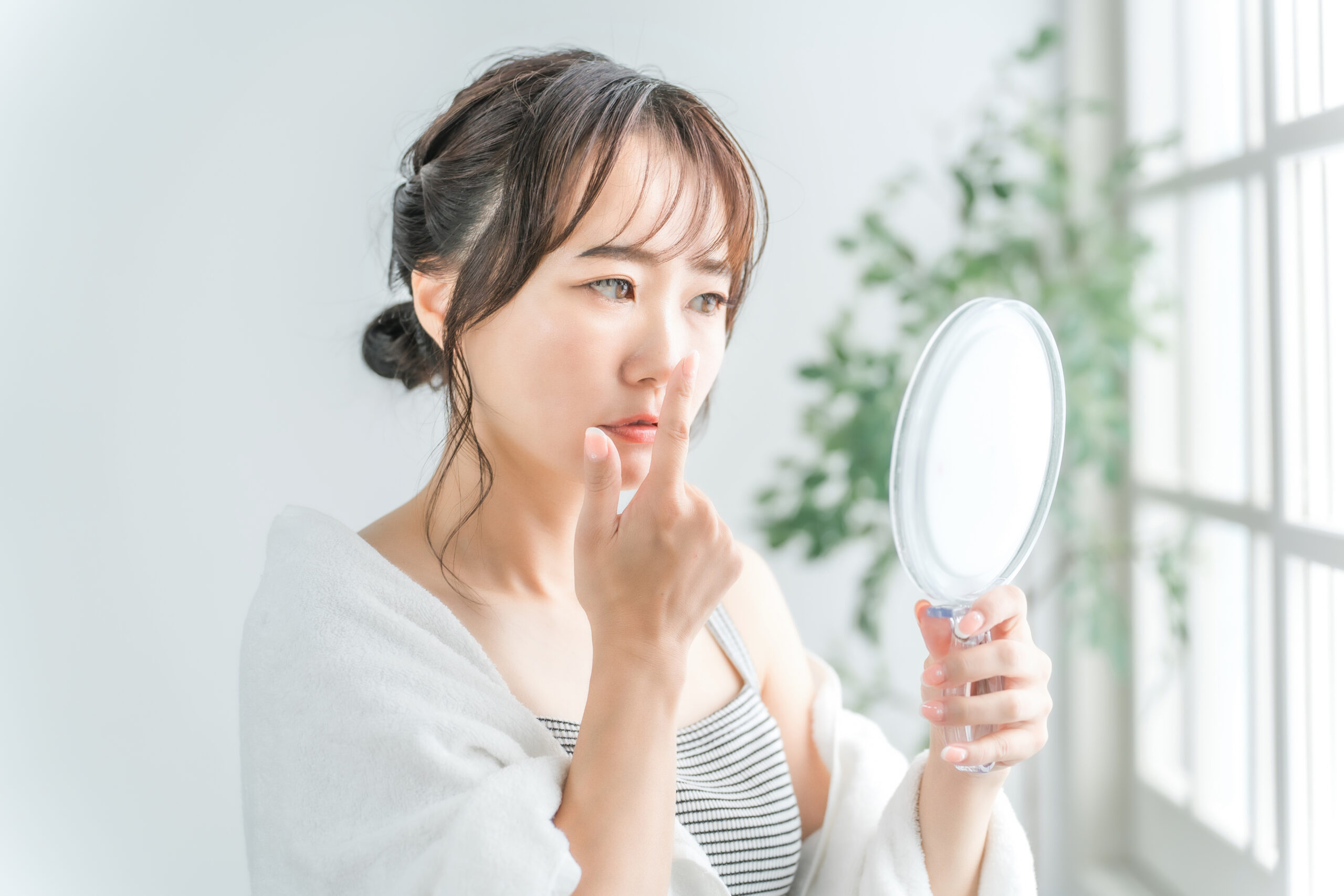 鏡を見て鼻を気にする女性